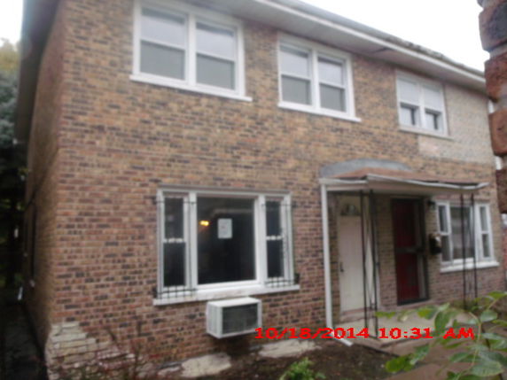 Front view of a two-story brick house with a covered entrance and multiple windows.