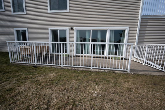 Front view of a beige building facade with sliding glass doors and white railing.