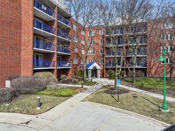 Front view of a multi-story brick apartment building with balconies.