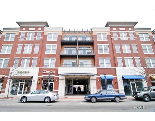 Front view of a four-story commercial and residential building with a brick facade and storefronts on the ground floor.