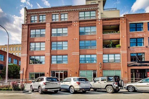 Front view of a multi-story brick building with large windows.
