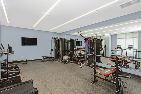 Indoor gym with various exercise equipment, including weights and treadmills.