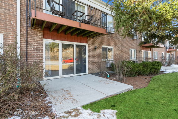 Exterior view of a brick apartment building with patios and balconies.