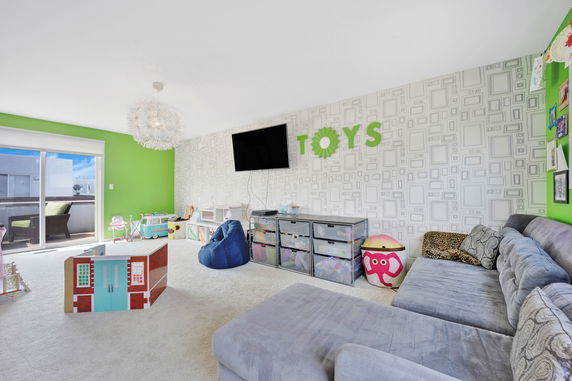 Indoor play area with toys, a sofa, and colorful wall decorations.