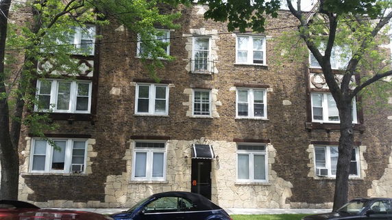 Front view of a three-story brick apartment building with multiple windows.