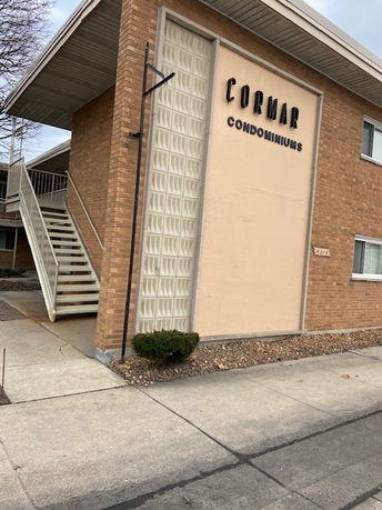 Front view of a two-story brick condominium building with external stairs.