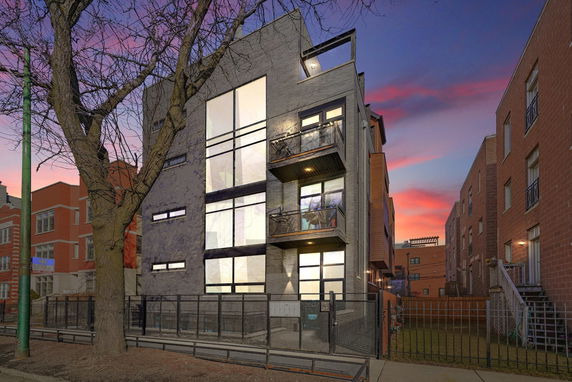 Front view of a modern multi-story building with large windows and balconies