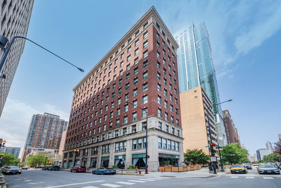 Front view of a multi-story red brick building on a city street corner.