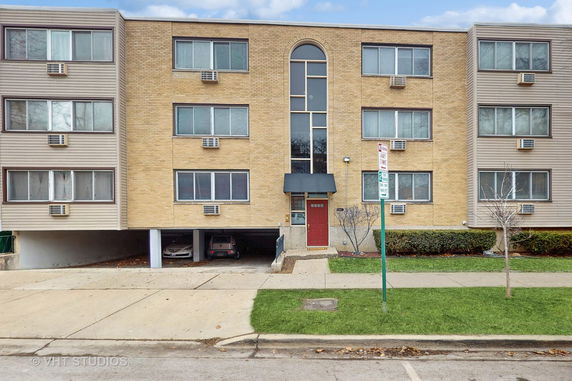 Front view of a multi-story building with parking space underneath.