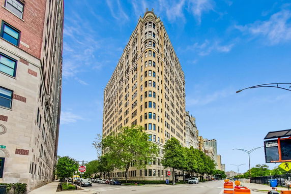 View of a tall apartment building on a city street corner.