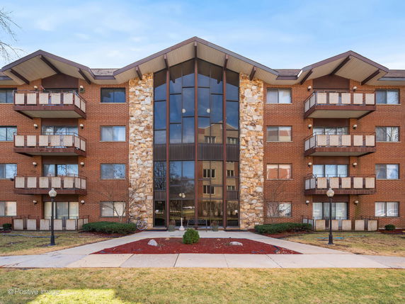 Front view of a multi-story apartment building with balconies and large central windows.