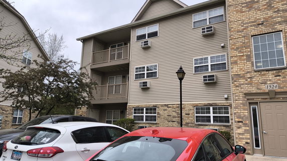 Front view of a multi-story building with balconies and air conditioning units.