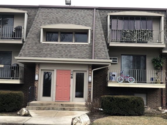 Front view of a two-story residential building with balconies and a central entrance.