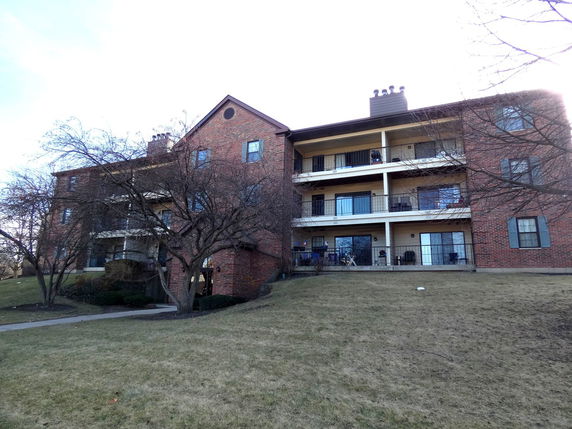 Front view of a multi-story brick apartment building with balconies.