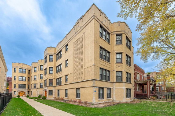 Front view of a brick multi-story apartment building with architectural details.