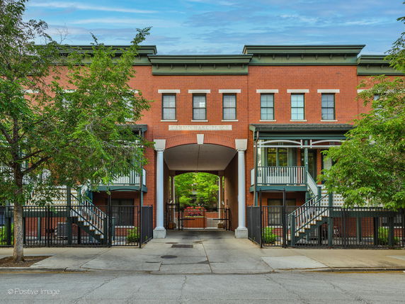 Front view of a brick building with a central archway and two staircases leading to porches.