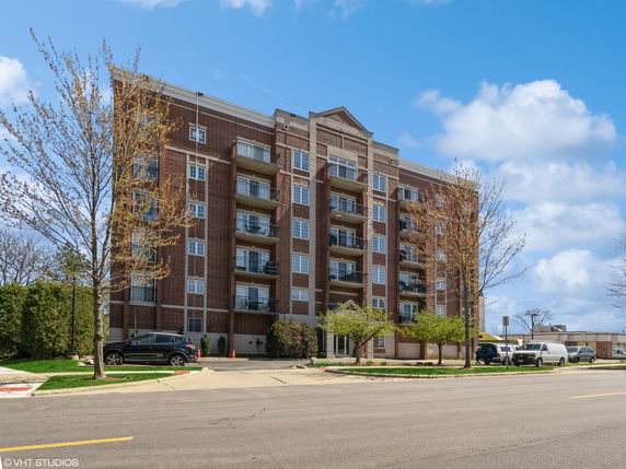 Front view of a multi-story brick apartment building with balconies.