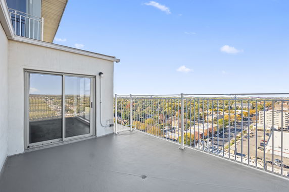 Rooftop balcony with railing and a view of the cityscape below.