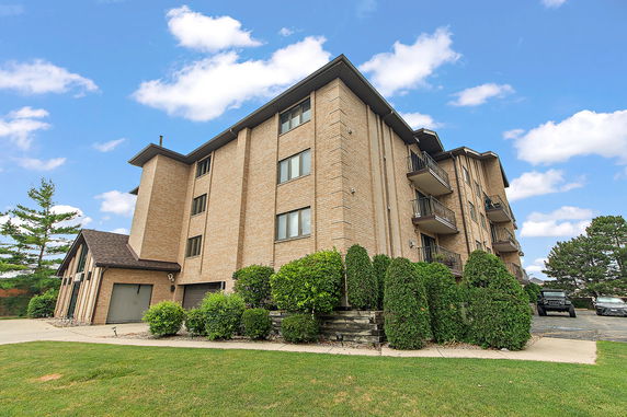 Front view of a multi-story brick apartment building with balconies.