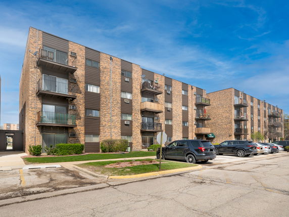 Front view of a multi-story brick apartment building with balconies.