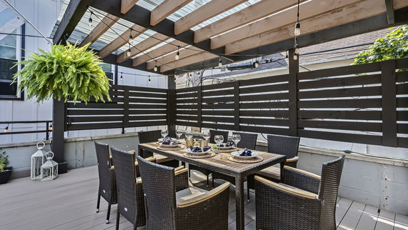 Outdoor rooftop seating area with a pergola and dining table set.