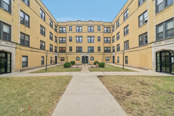 Front view of a multi-story brick apartment building with central courtyard.