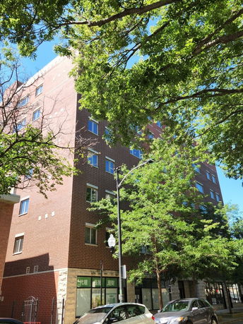 Front view of a multi-story brick building with trees in front.