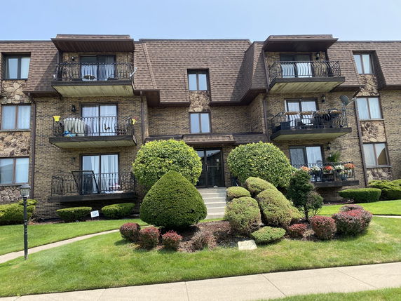 Front view of a multi-story brick apartment building with balconies.