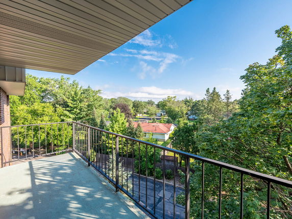 Panoramic view from a balcony overlooking a residential area with trees and houses.