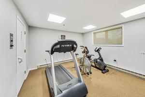 Room with fitness equipment including a treadmill and stationary bike.