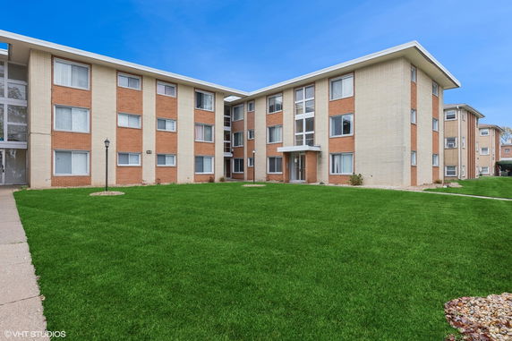 Front view of a three-story residential building with brick and siding exterior.