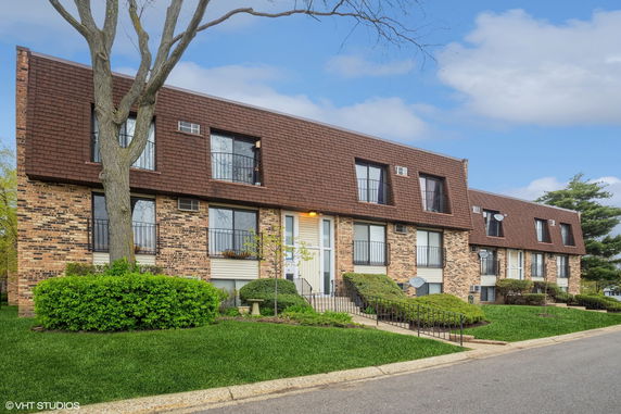Front view of a two-story building with brick facade and brown roof tiles.