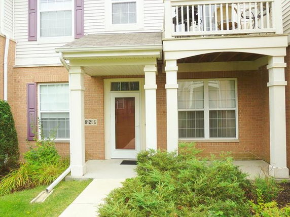 Front view of a two-story house with a small porch and upper balcony.