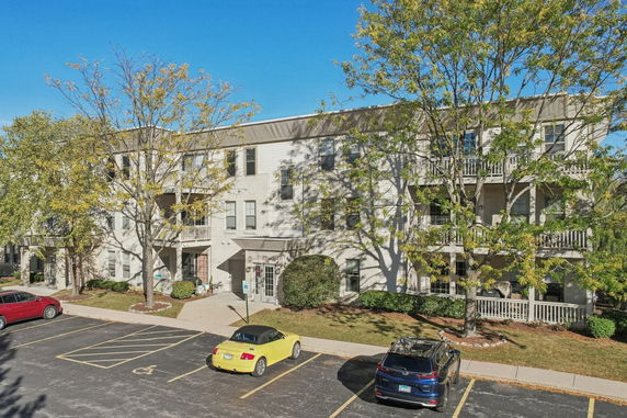 Front view of a three-story apartment building with balconies and parking area.