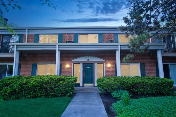 Front view of a two-story brick building with a green door and white columns.