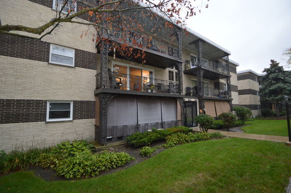 Front view of a three-story apartment building with balconies and decorative railings.