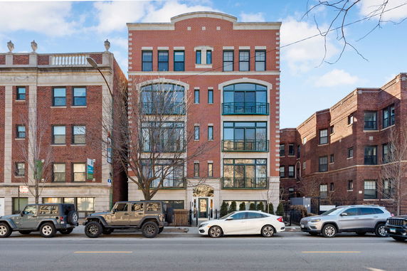 Front view of a multi-story brick apartment building with large windows.