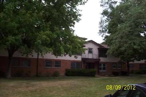 Front view of a two-story building with a brick facade and trees in front.