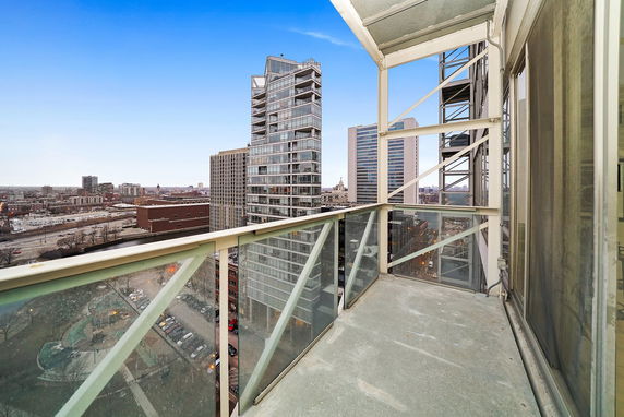 View from a building balcony overlooking a cityscape with multiple modern high-rise buildings and a clear sky.