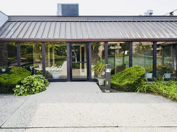 Front view of a building with glass doors and a sloped metal roof.