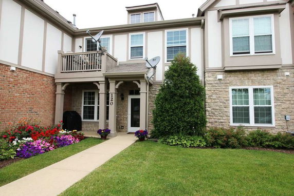Front view of a two-story house with a balcony and stone facade.