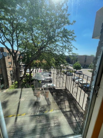 View from a balcony showing a parking lot and trees.