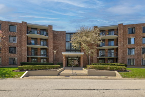 Front view of a multi-story brick apartment building with balconies.