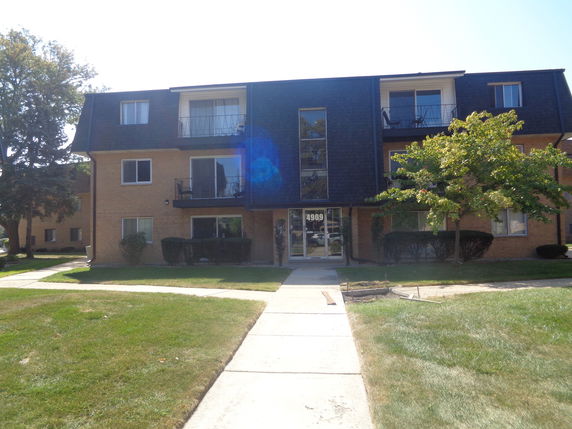 Front view of a three-story apartment building with balconies and a central entrance.