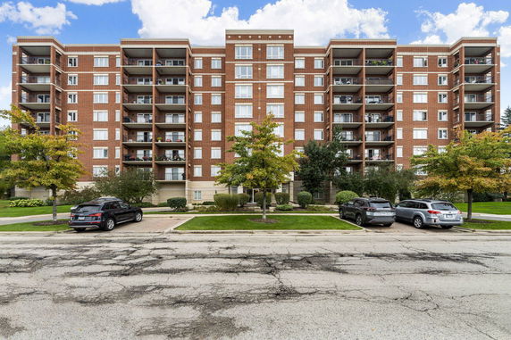 Front view of a multi-story brick apartment building with balconies.