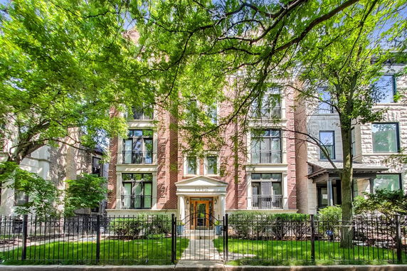 Front view of a multi-story brick building with large windows and a gated entrance.