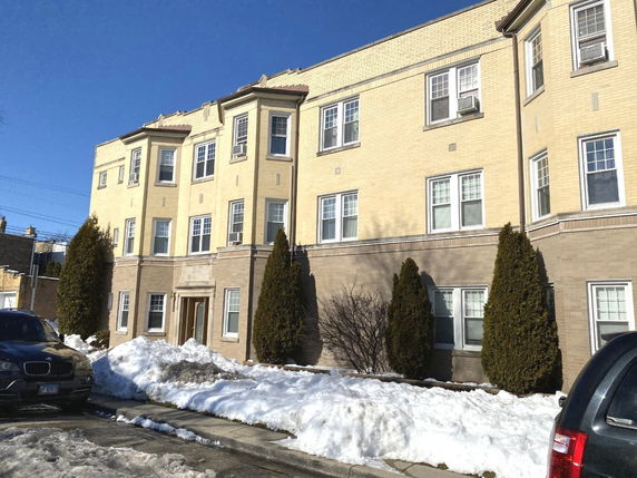 Front view of a multi-story residential building with beige brick exterior.