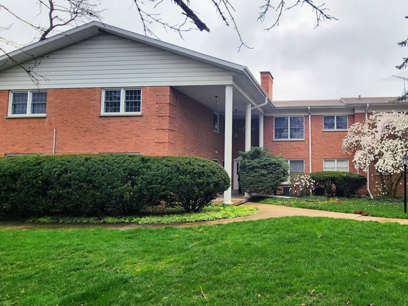 Front view of a two-story brick house with a large portico and white pillars.