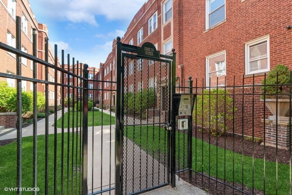 Front view of a multi-story brick building with a gated entrance.