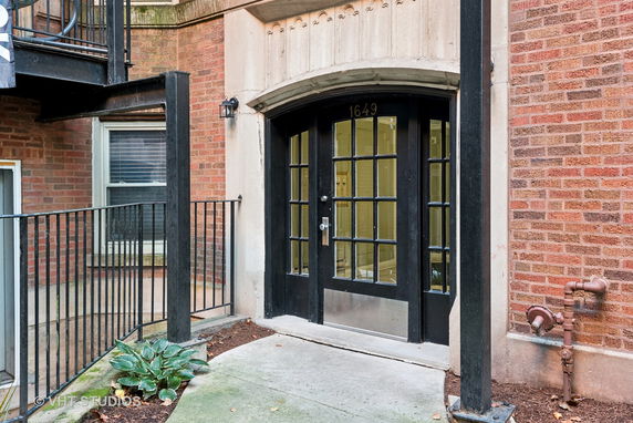 Front view of a building entrance with a black door and brick exterior.